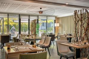 a restaurant with tables and chairs and windows at Hôtel Restaurant Athena Spa in Strasbourg