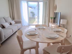 a white living room with a table and a couch at Garden House 2 in São Vicente Ferreira