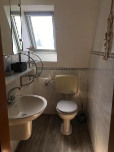 a bathroom with a toilet and a sink and a window at Ferienhaus Familie Lehmann in Borkum +5 photos