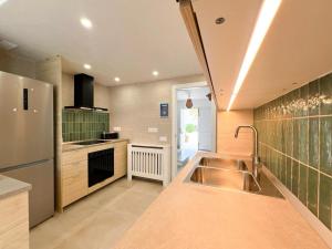 a kitchen with a sink and a stainless steel refrigerator at Villa in Playa den Bossa, 5 min SupermarketBBQ in Sant Jordi