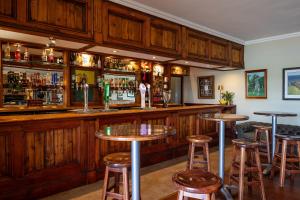 a bar with wooden cabinets and bar stools at Gowrie Farm Golf Lodge in Nottingham Road