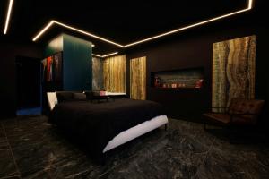 a bedroom with a large bed and a chair at Suite Dark Luxe avec Écran géant de cinéma et jacuzzi in Clary