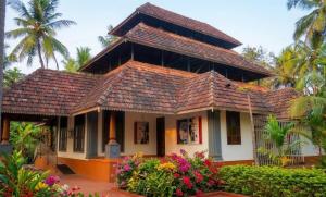a house with a tiled roof and some flowers at Amma Stays and Trails in Kotikulam