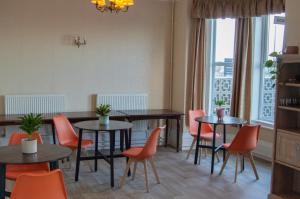 a dining room with tables and orange chairs at The Chateau by MPH Holidays in Great Yarmouth