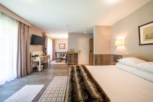 a hotel room with a bed and a living room at La Barrière de Transinne in Libin