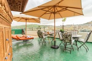a patio with a table and chairs and umbrellas at Riad May Fes Original & Spa in Fez