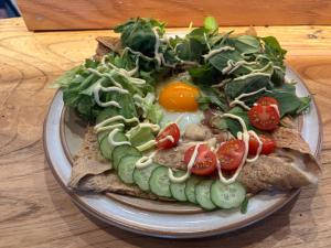 a plate of food with an egg and vegetables at 静かな森の古民家ステイ Tunagiつなぎ in Nishiwaga