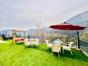 a patio with tables and chairs and an umbrella at The Pranav Retreat A Premium Property in Nainital