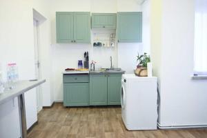 a kitchen with green cabinets and a white refrigerator at Міні Готель Особняк in Lviv