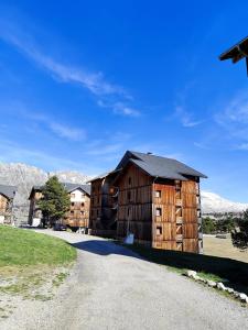 a large wooden building with mountains in the background at Marla 52 in Le Dévoluy