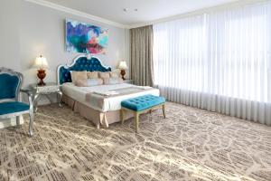 a bedroom with a king sized bed and a blue chair at Bristol Central Park Hotel in Chişinău