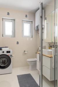 a bathroom with a washing machine and a toilet at Holiday home with several apartments, a pool, sea views and a barbecue near Split in Podstrana +130 photos