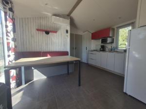 a kitchen with a table and a refrigerator at The Mobil home Confort Clim / 2 Chb / 5 Pers in Lagorce