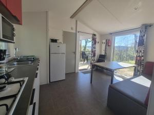 a kitchen with a refrigerator and a table in it at The Mobil home Confort Clim / 2 Chb / 5 Pers in Lagorce