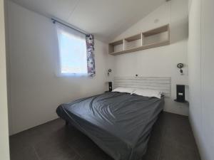 a small bedroom with a bed and a window at The Mobil home Confort Clim / 2 Chb / 5 Pers in Lagorce