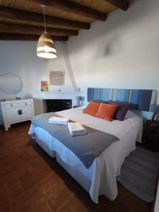 a bedroom with a large bed with orange and blue pillows at Monte Costa Raiz in Mértola +24 photos