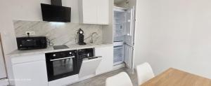 a kitchen with white cabinets and a black appliance at LE 1 BIS - T2 tout équipés in Sainte-Savine +7 photos