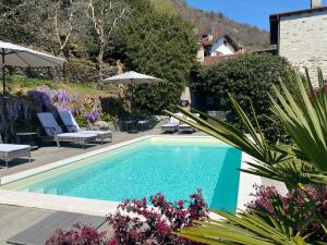 a swimming pool in a yard with chairs and umbrellas at Casa Artis in Gravedona