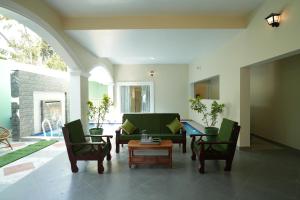 a living room with chairs and a couch and a table at Green Resort Pondicherry in Pondicherry