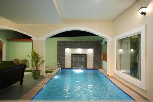 a large swimming pool in a room with a fireplace at Green Resort Pondicherry in Pondicherry