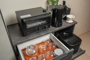 a counter with a toaster oven and glasses on it at 在-Zai- in Beppu