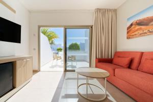 a living room with a red couch and a table at Hotel Lanzarote Village in Puerto del Carmen