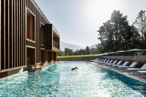 a person swimming in a swimming pool next to a building at Falkensteiner Hotel Kronplatz - The Leading Hotels of the World in Brunico +47 photos