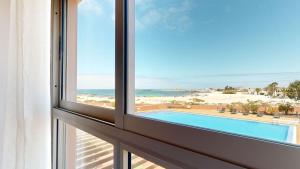 a window with a view of the beach and a swimming pool at Beach Apartment Marfolin 06 El Cotillo in El Cotillo