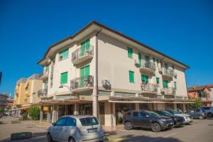 a large building with cars parked in a parking lot at Centric apartment by the beach in Eraclea Mare