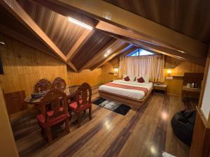 a bedroom with a bed and a table and chairs at Hotel The Red Apple in Manāli