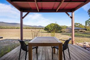 a wooden table and chairs on a wooden deck at Blaze Rock Retreat in Halls Gap