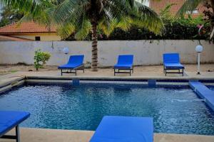four blue chairs and a swimming pool with a palm tree at la villa du parc in Niaga