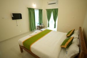 a bedroom with a large bed with green curtains at Green Resort Pondicherry in Pondicherry