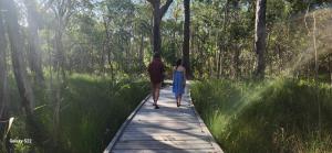 a man and a woman walking on a wooden path at Bushwalk Escape 1770 in Agnes Water +8 photos