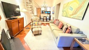 a living room with a couch and a flat screen tv at Espaçoso Apto triplo a 300 mts do Centrinho Capivari in Campos do Jordão