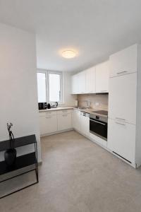 a white kitchen with white cabinets and a black stove at Apartments Nilada in Zirl