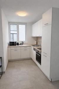 a white kitchen with white cabinets and a window at Apartments Nilada in Zirl