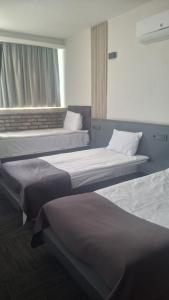 a room with three beds and a window at Hotel ABBARA in İzmir