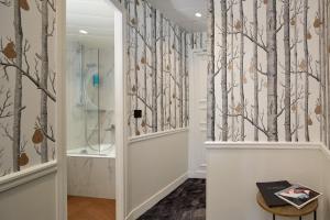 a bathroom with a shower and trees wallpaper at Hôtel le Royal Rive Gauche in Paris