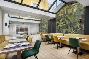 a restaurant with tables and chairs and a wall with plants at Hôtel le Royal Rive Gauche in Paris