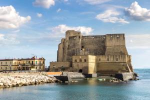 an old castle sitting on the water near the ocean at Angioino Central in Naples