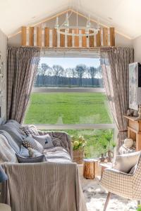 a bedroom with a bed and a large window at Kemphaontje is a Magic Tiny House with a view in Anloo
