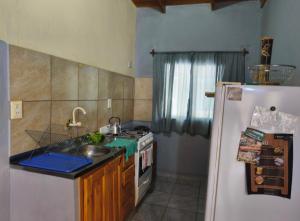 a kitchen with a white refrigerator and a sink at Silvia Apart Confort in Puerto Iguazú