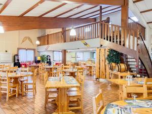 a restaurant with wooden tables and chairs and a staircase at Chalet Ma Neou Village Vacances in Les Angles