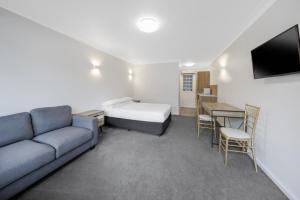 a living room with a couch and a bed and a table at Elizabethan Lodge in Melbourne
