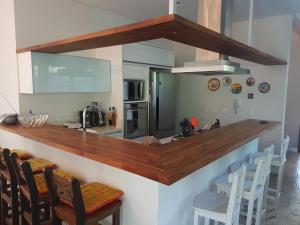 Una cocina con una encimera con sillas y un fregadero. en Casa Luxo, en Balneário Camboriú