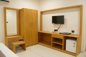 a room with a desk with a television and a cabinet at Palm Glow Resort in Daisara