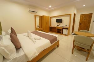a bedroom with a bed and a desk and a television at Palm Glow Resort in Daisara