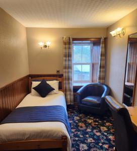 a hotel room with a bed and a blue chair at The Orkney Hotel in Kirkwall