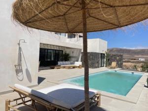 a villa with a swimming pool and an umbrella at Casa Victoria El Roque in Roque